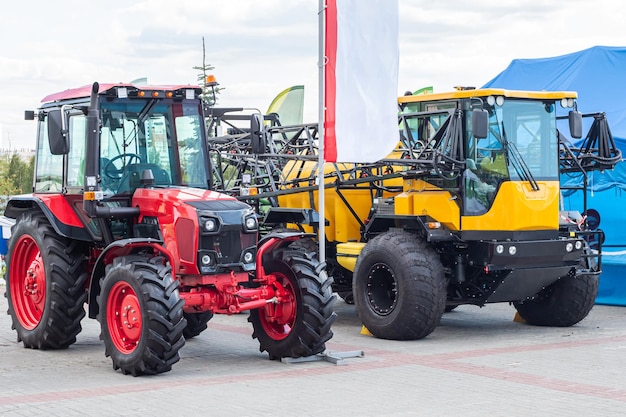 Trattore a ruote rosse e veicolo fuoristrada agricolo giallo con attrezzatura per l'irrorazione del campo