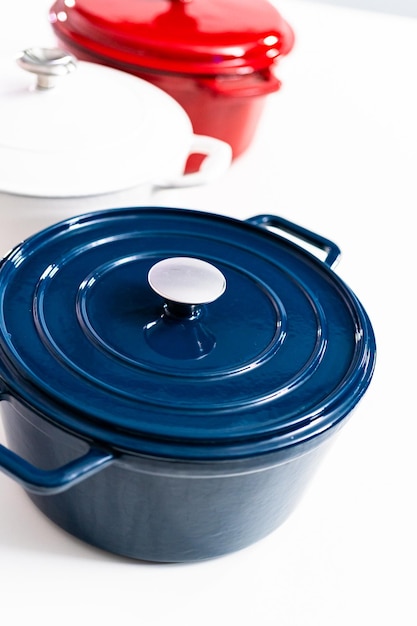 Red, white and blue enameled cast iron covered round dutch ovens on a whjite background.