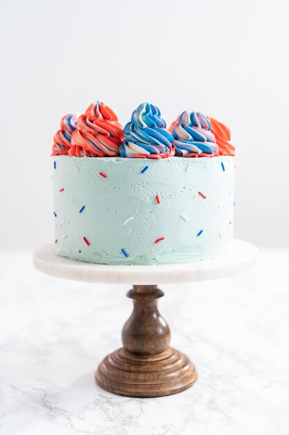 Red, white, and blue round vanilla cake with buttercream frosting for July 4th celebration.