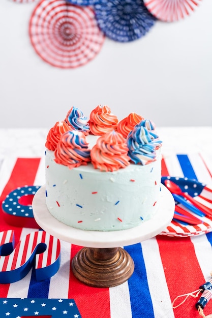 Red, white, and blue round vanilla cake with buttercream\
frosting for july 4th celebration.