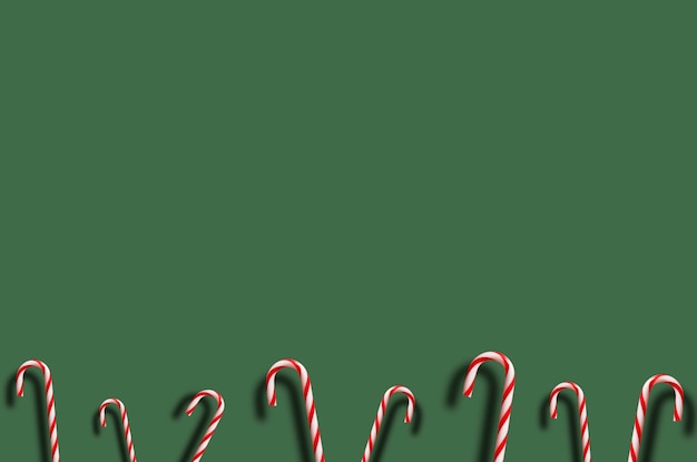 Red and white candy canes of various sizes on green, flat lay