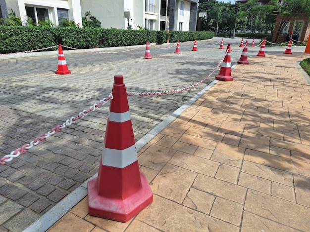 a red and white caution cone is on the sidewalk.