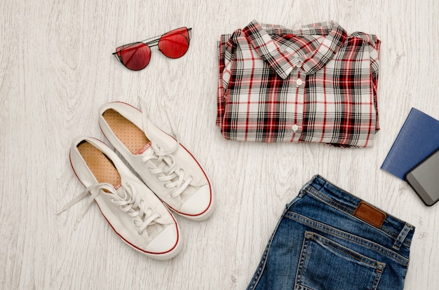 Red and white checkered shirt, glasses, sneakers, jeans, phone and passport, Fashionable concept,  