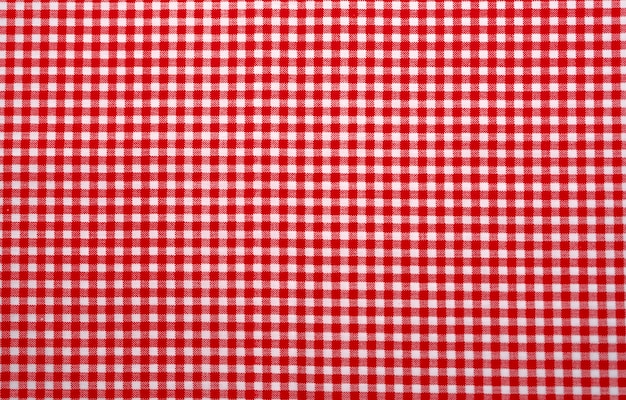 Red and white checkered tablecloth. Top view table cloth texture background. Red gingham pattern fabric. Picnic blanket texture.
