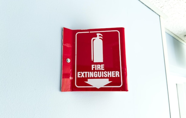 Photo red and white fire extinguisher sign on wall indicating emergency safety equipment presence