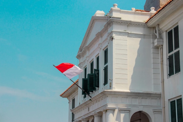 The red and white flag fluttering in the window of the white building
