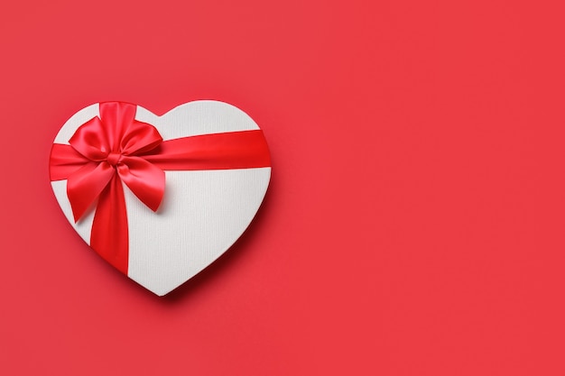 Red white gift in shaped of heart isolated on red