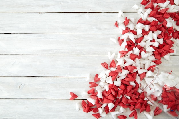 red and white heart shapes spilling from jar on wooden table