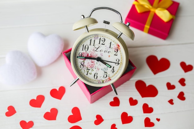 木製の背景に赤と白のハート 箱の中のレトロな時計 聖バレンタインの日のコンセプト 愛とロマンチックな写真 休日のためのはがき プレゼントのアイデア