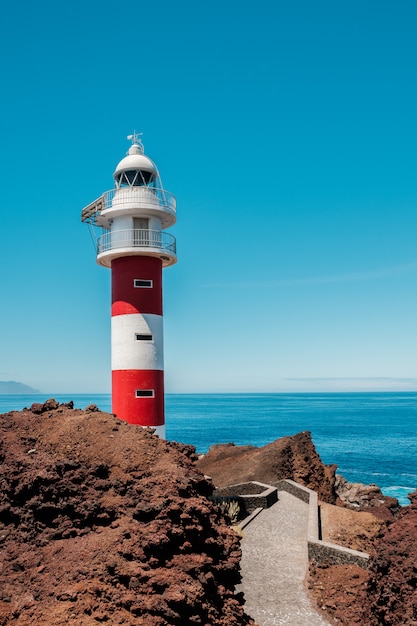 Red and white lighthouse at the end of the path