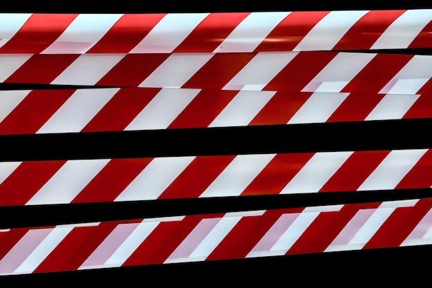 Red and white lines of barrier tape prohibit passage tape on\
black isolate background