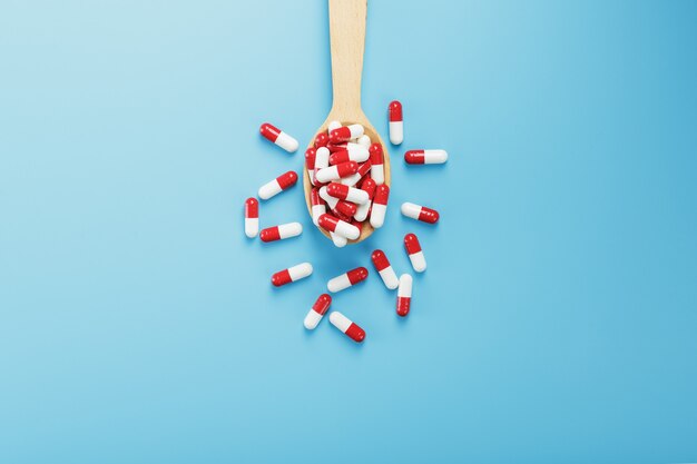 Red and white pill capsules on a blue background. Close-up of Free space Top view