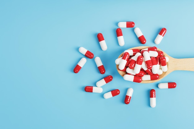 Red and white pill capsules on a blue background. Close-up of Free space Top view