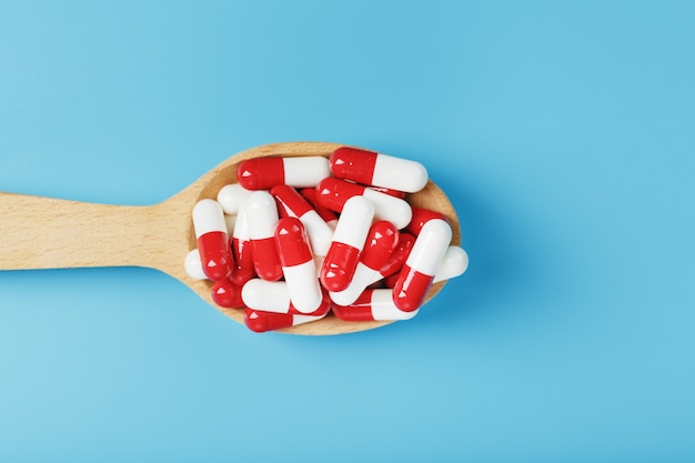 Red and white pill capsules on a blue background.