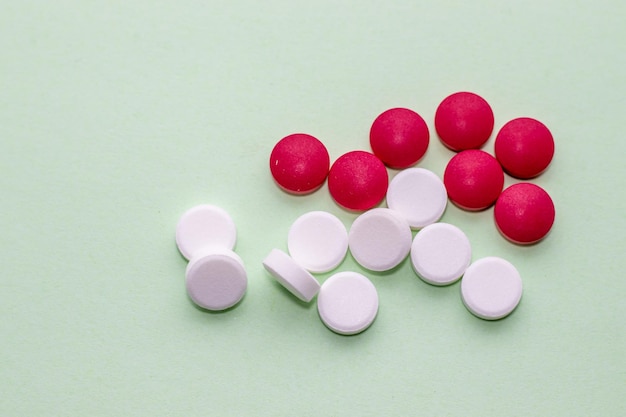 red and white pills in womans hand or on green background healthcare concept round tablets