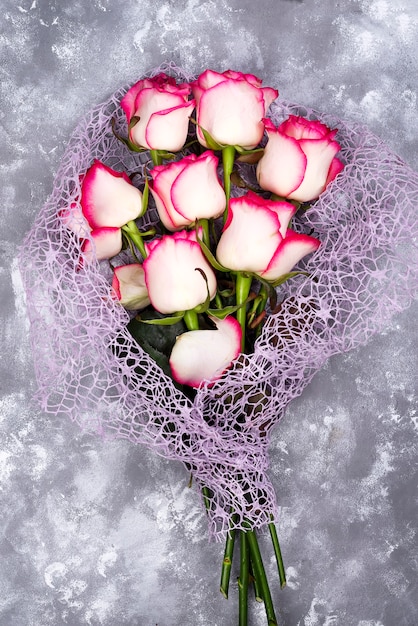 Foto mazzo rosso del fiore della rosa di bianco sulla tavola di pietra.