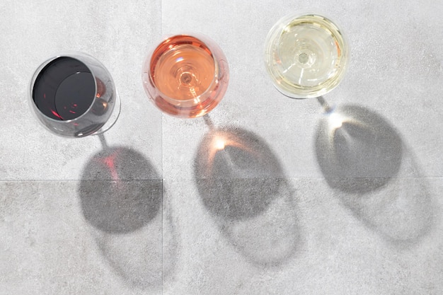 Red white and rose wine in wine glasses isolated on concrete background with copy space Top view