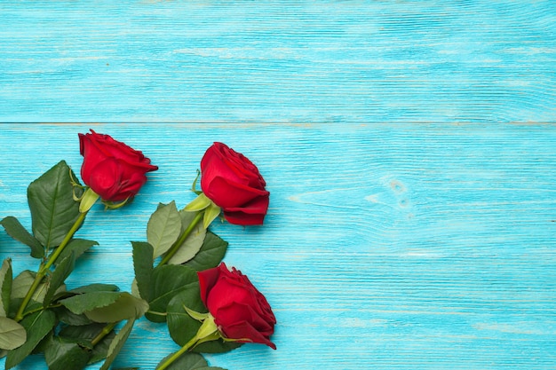 Red and white roses over blue wooden table