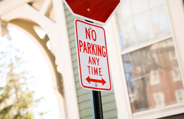 A red and white sign that says no parking any time.