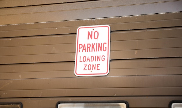 Red and white sign that says no parking loading zone.