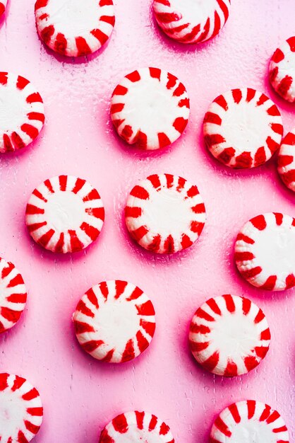 Above red and white striped round mint candies on pink tray