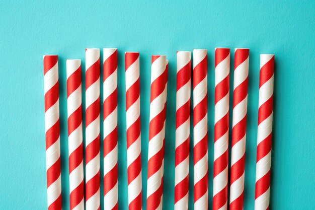 Red and white striped straws on a teal background