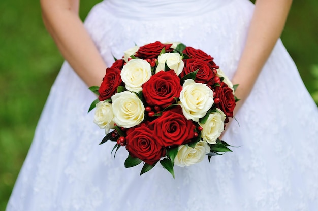 Red and white wedding bouquet of roses in the hands of the bride