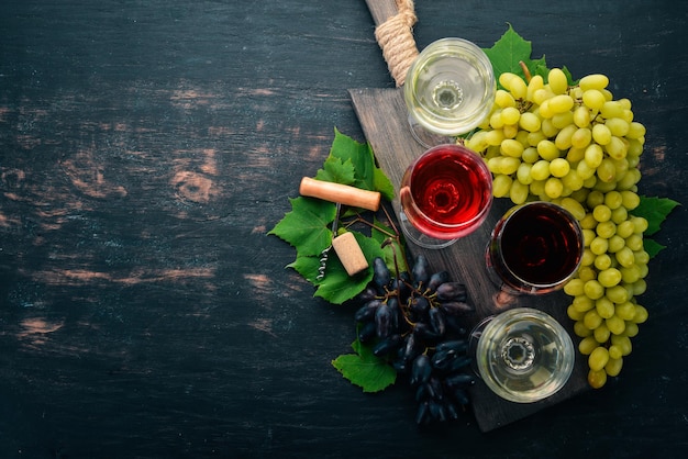 Red and white wine in the glasses Grape On a black wooden background Free space for text Top view