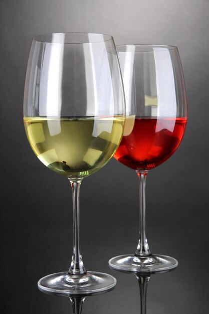 Red and white wine in glasses on grey background