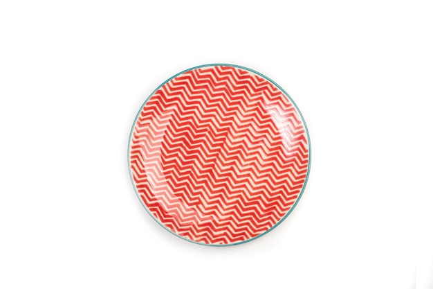 A red and white zigzag decoration ceramic round dish on a white background in a top view