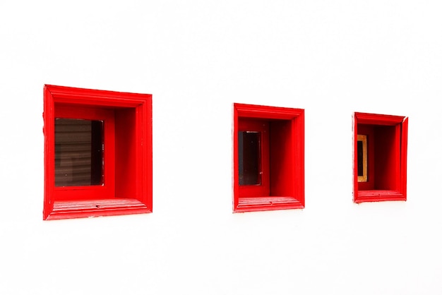 Red windows on white wall of building