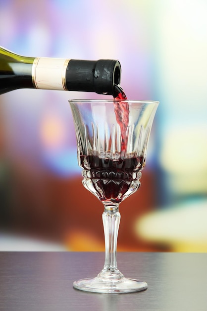 Red wine being poured into wine glass on bright background