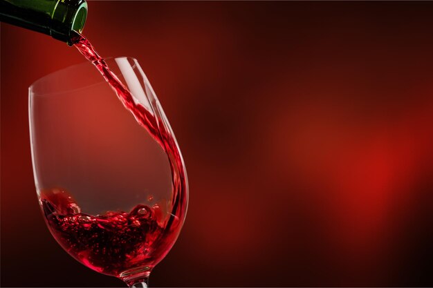 Red wine being poured in wineglass, closeup