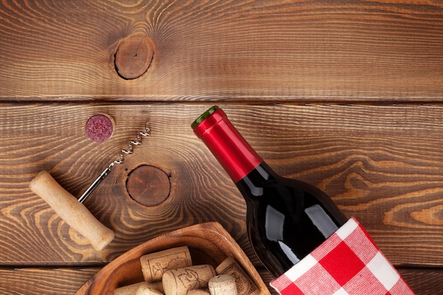 赤ワインボトル、コルク栓抜きとコルク栓抜きのボウル。素朴な木製のテーブルの背景の上からの眺め