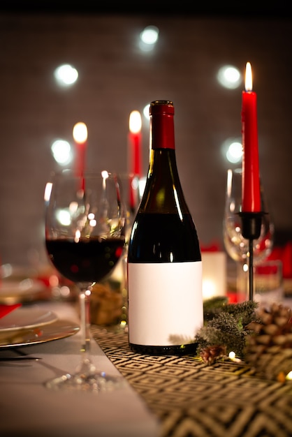 빨간색과 금색 반짝이 장식에 와인 한 잔과 함께 크리스마스 휴일 축제 파티 테이블에 레드 와인 병