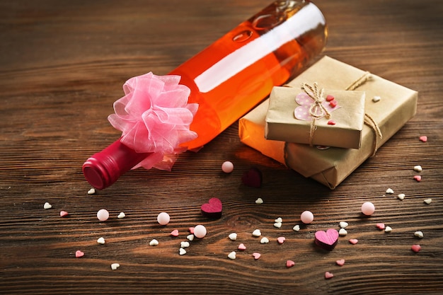 Red wine bottle and gift box on wooden background