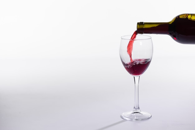 Red wine bottle pour glass on white background with copy space