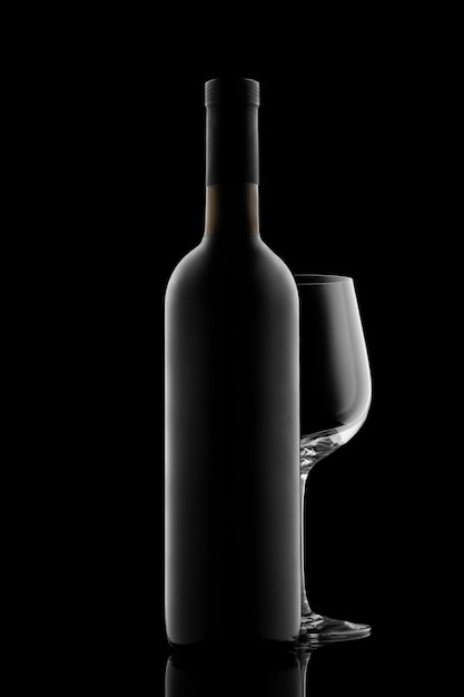 Red wine bottle and wine glass isolated on black background