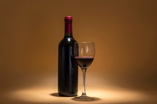 Red wine bottle and wine glass placed on a warm brown background