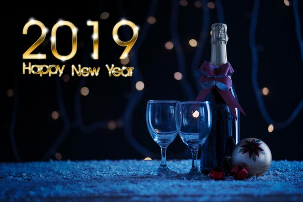 크리스마스 볼과 2019년 새해 축하 텍스트가 있는 레드 와인 병 테이블 위의 눈과 보케 배경으로 촬영