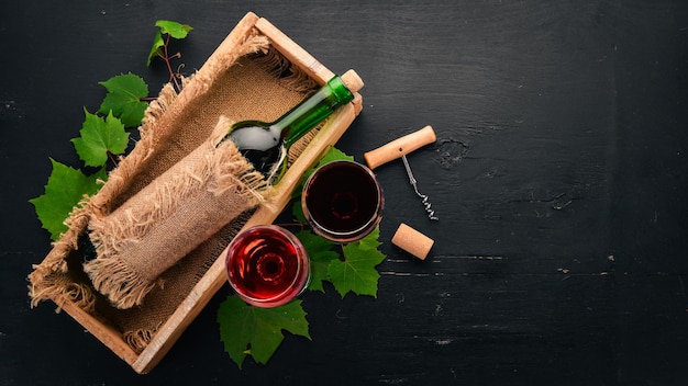 Red wine in a bottle with a glass and grapes On a black wooden background Free space for text Top view