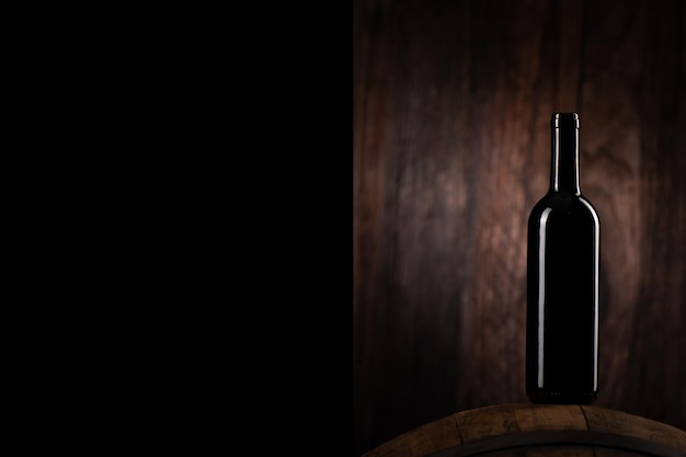 A Red wine bottle on wodden barrel with a wooden backgorund