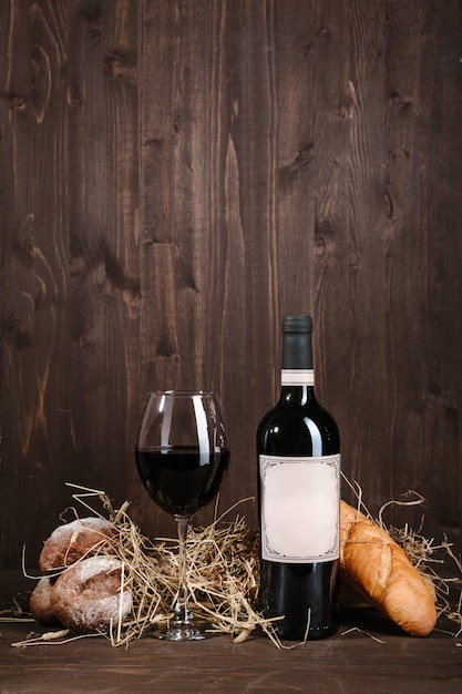 Red wine composition with bread bottle and wineglass on brown wooden table