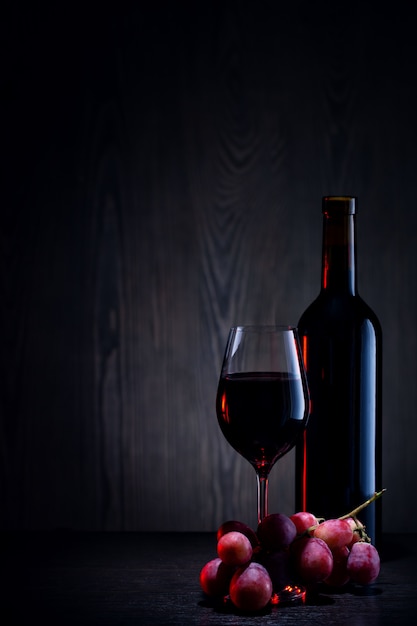 Red wine in glass and bottle and bunch of grapes