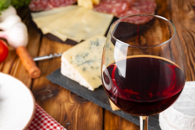 Red wine glass and cheese blocks on wooden table