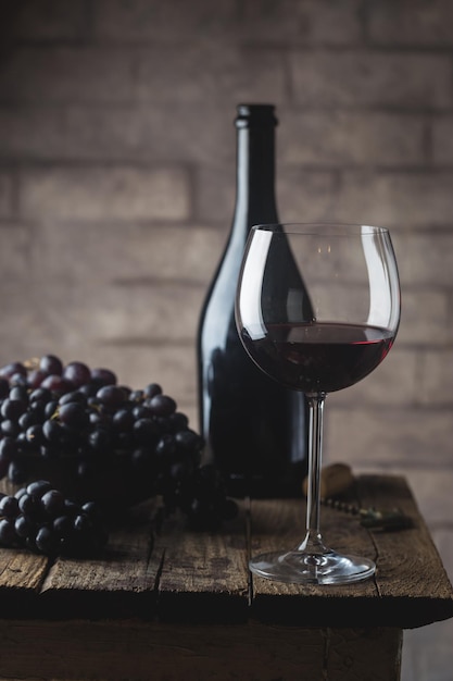 Red wine in a glass and ripe grapes on wooden table