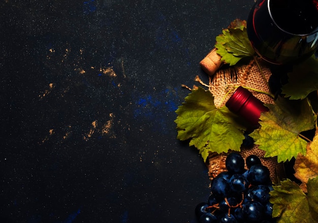 Red wine in glass vine and grapes black background top view