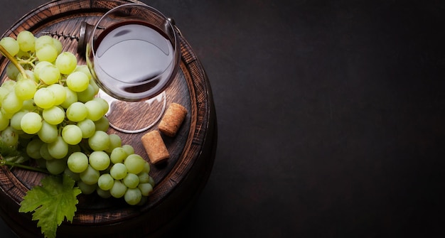 Red wine glass and white grape on old barrel