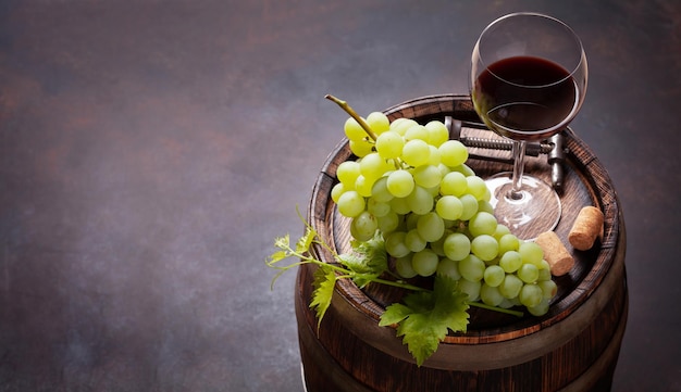 Red wine glass and white grape on old barrel