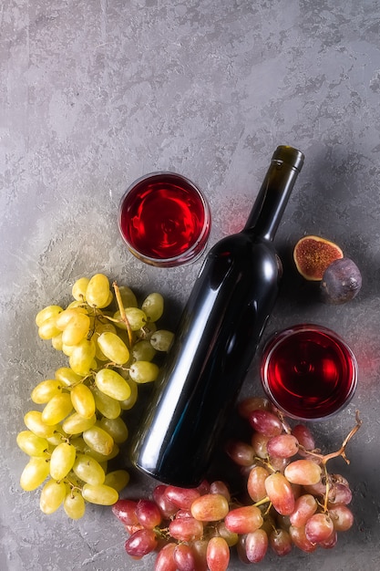 Red wine in glasses, bottle of wine, figs, and grape